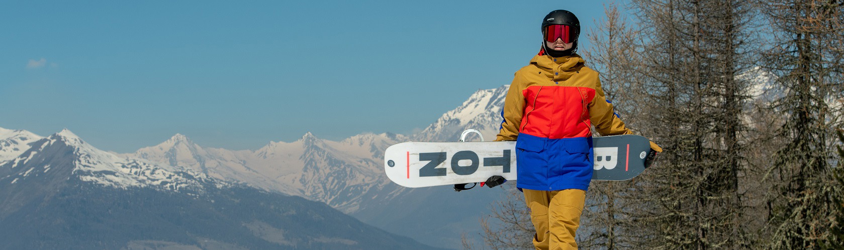 A person holding their Burton snowboard in the mountains 